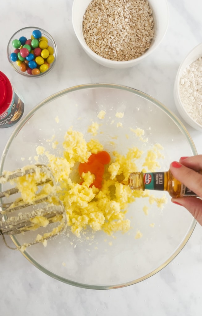 Ingredients being mixed together in a large glass bowl using an electric whisk. 