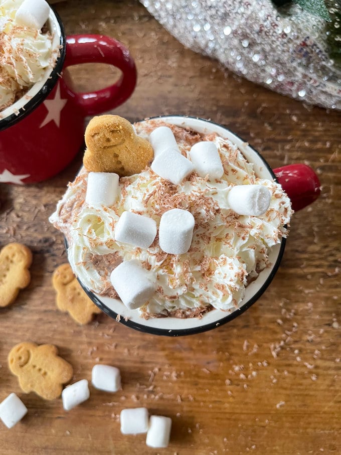 Close up of top of the hot chocolate, garnish with whipped creamed, grated chocolate, mini marshmallows and gingerbread man. 