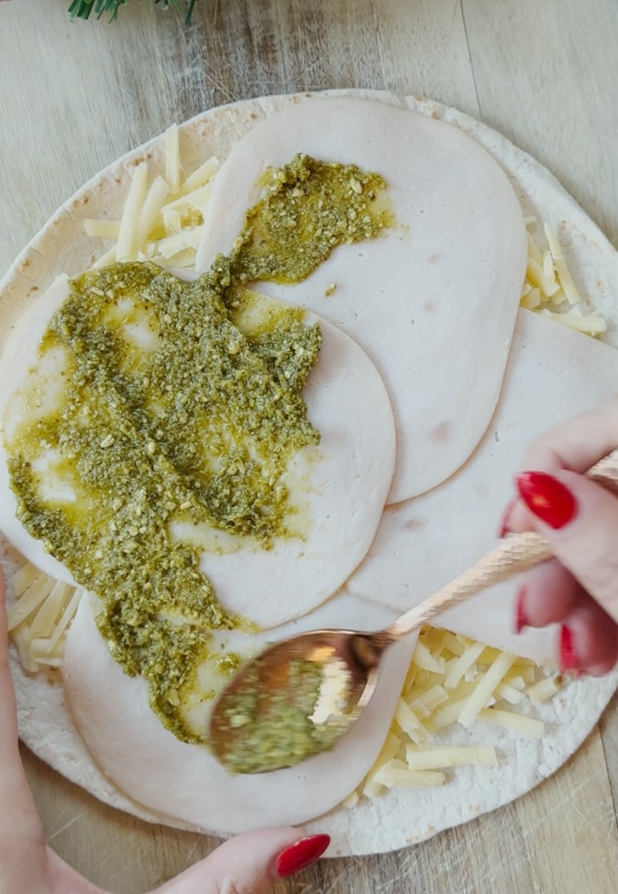 Ingredients being spread into the tortilla. 
