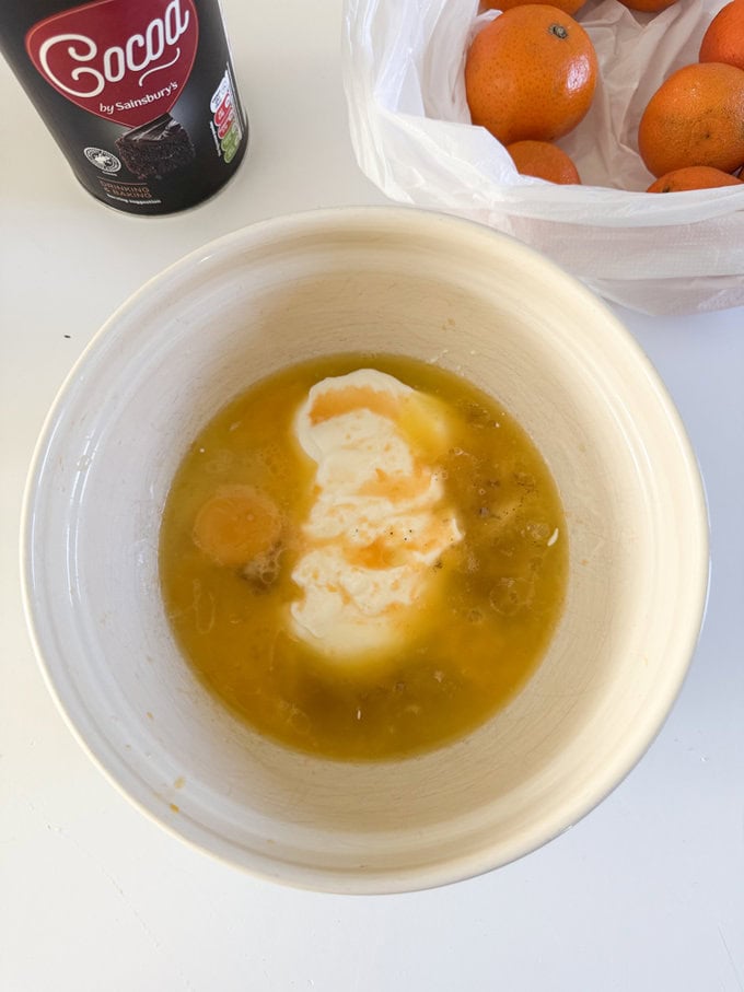 Ingredients  being added to a cream colored mixing bowl. 