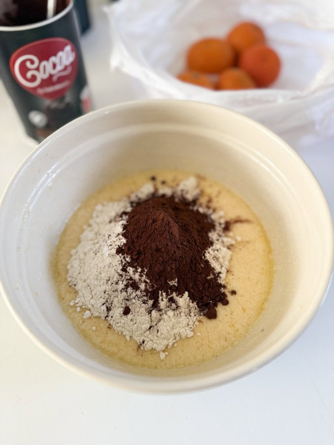 Ingredients  being added to a cream colored mixing bowl. 