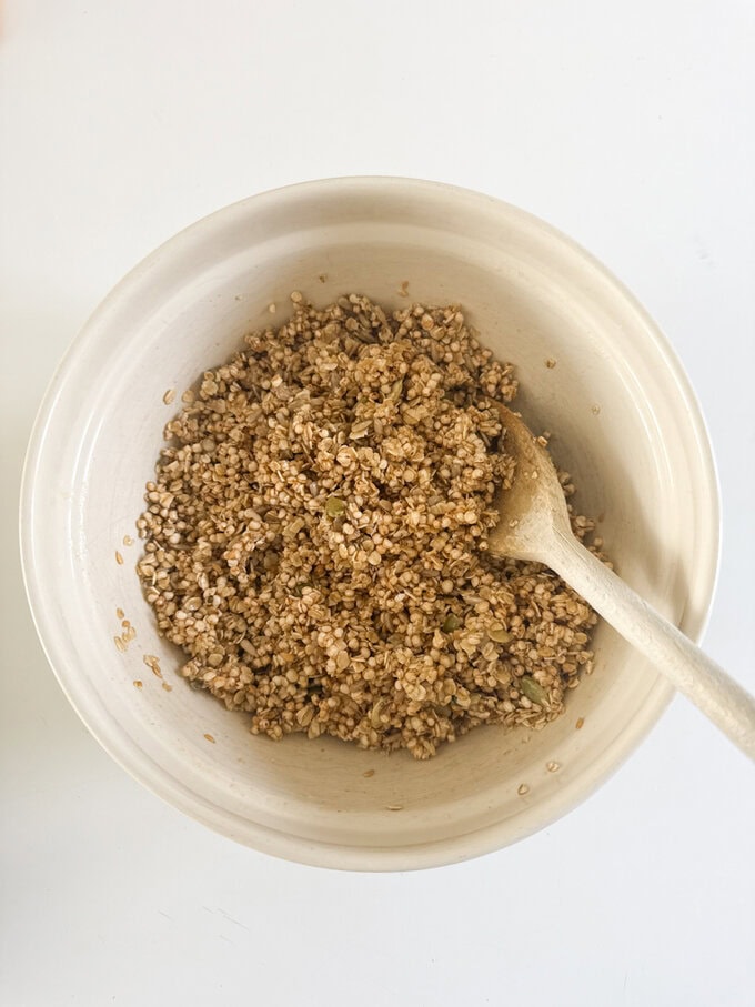 Quinoa and all the other ingredients being mixed up in a bowl with a wooden spoon. 