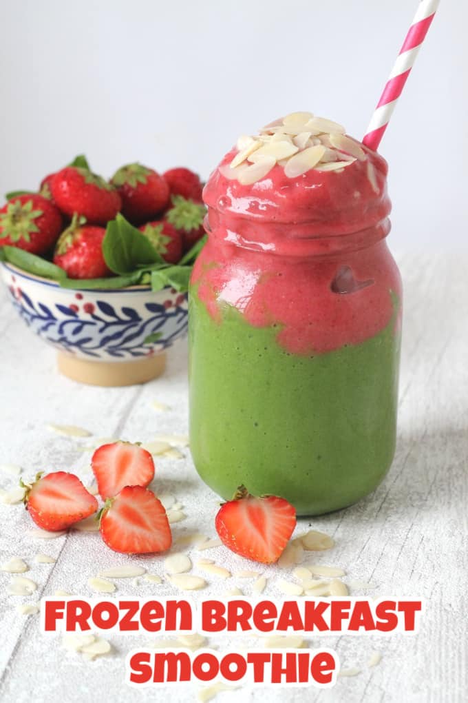 A pink and green frozen smoothie served in a glass jar with a pink striped straw and almond slices on top. 