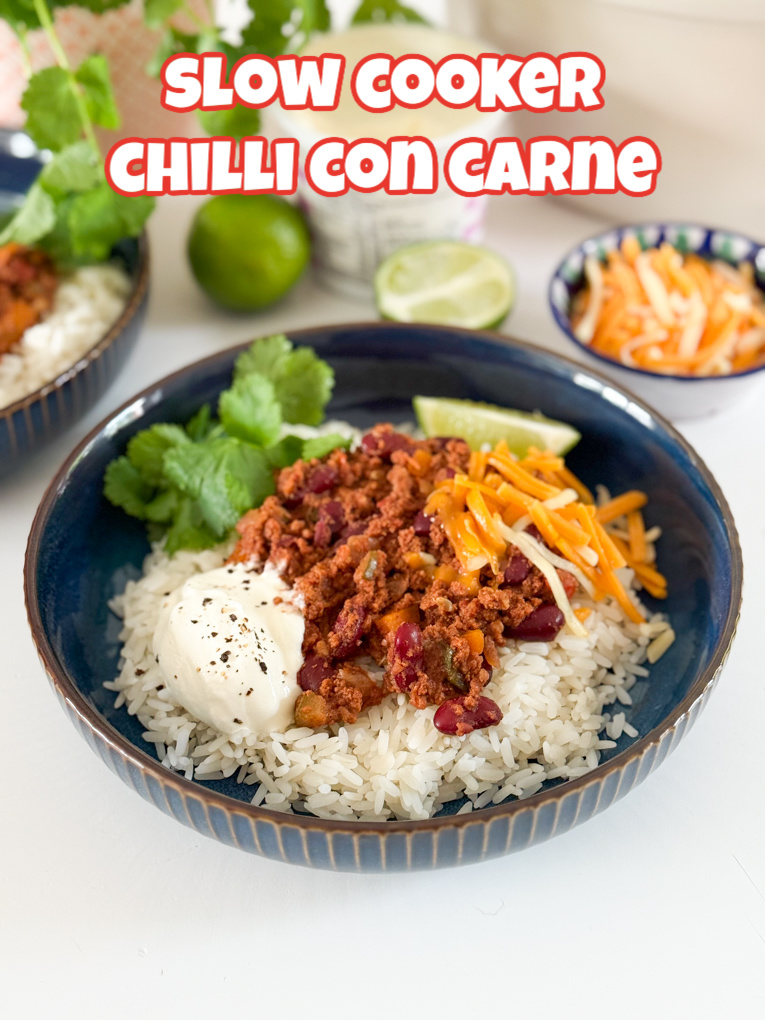 Served with white rice,grated cheese. And garnished with a slice of lime and a sprig of coriander. In a round dark blue bowl.